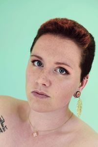 Close-up portrait of young woman against gray background