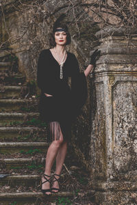 Portrait of young woman standing against tree