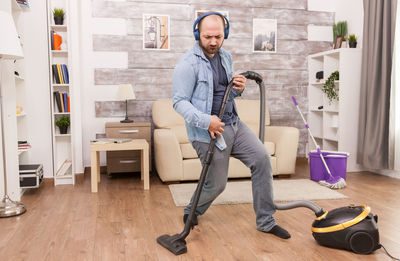 Carefree man listening music while cleaning home