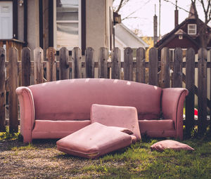 Abandoned sofa by fence in back yard