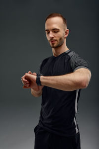 Portrait of young man using mobile phone against black background