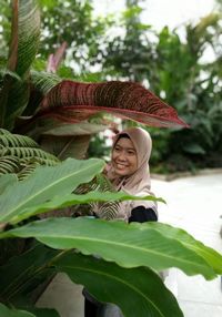 Portrait of smiling young woman against plants