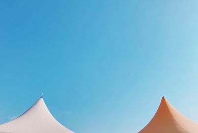 Low angle view of tents against clear blue sky