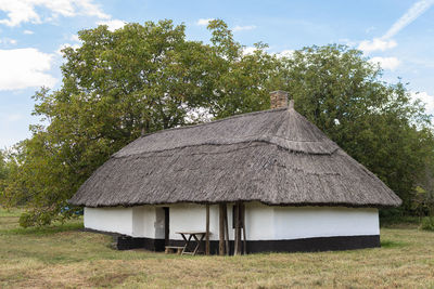 House amidst trees on field against sky