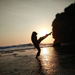 Silhouette man on beach against sky during sunset