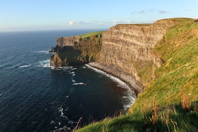 Scenic view of sea by cliff against sky