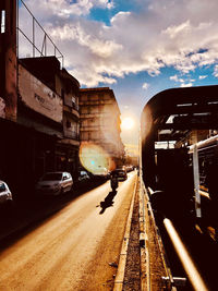 Cars on street in city against sky during sunset