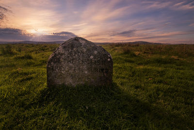 View of rock on field against sky during sunset