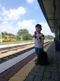 Boy standing on railroad track against sky