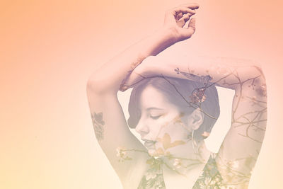 Double exposure of young woman and flowers against orange background
