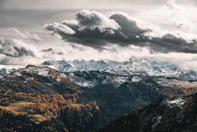 Dramatic sky over snow capped mountains in fall colors, saalbach, salzburg, austria.