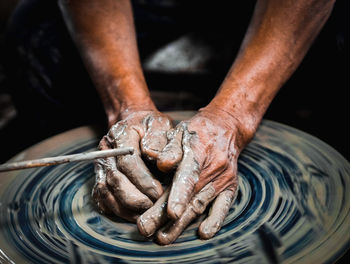 Cropped hands of man molding shape on pottery wheel