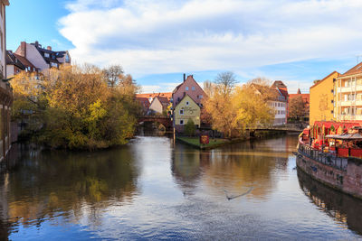 Houses by river against sky