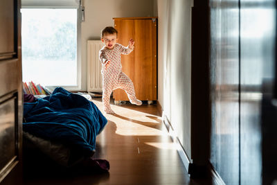 Full length of girl standing on bed at home