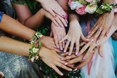 Midsection of friends and bride joining hands at wedding