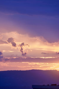 Silhouette building against dramatic sky during sunset