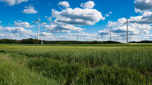 Wind turbines on field against sky