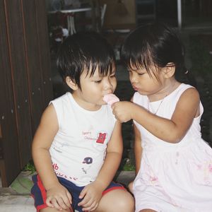 Sister feeding frozen food to brother