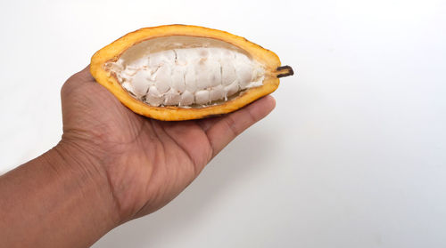 Close-up of hand holding ice cream against white background