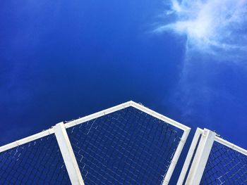 Low angle view of fence against blue sky