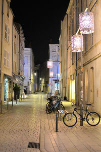 Bicycles on street amidst buildings at night