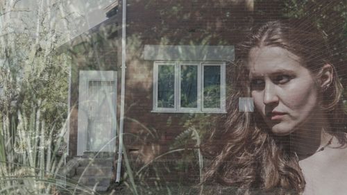 Young woman looking through window