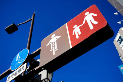Low angle view of road sign against blue sky