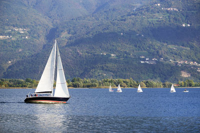 Sailboat sailing on sea against mountains