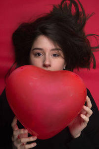 Portrait of young woman with red balloon