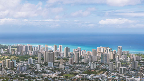 Modern buildings by sea against sky