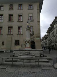 Statue on street against buildings in city