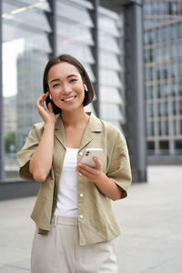 Portrait of young businesswoman standing against buildings