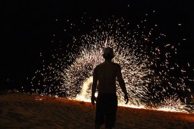 Rear view of silhouette man standing against sky at night