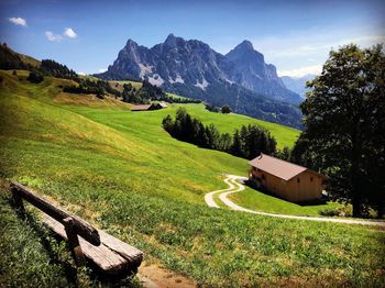 House on field by mountains against sky