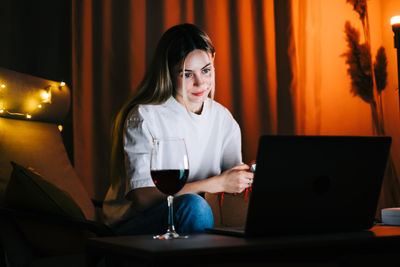 Young woman using mobile phone while sitting on table