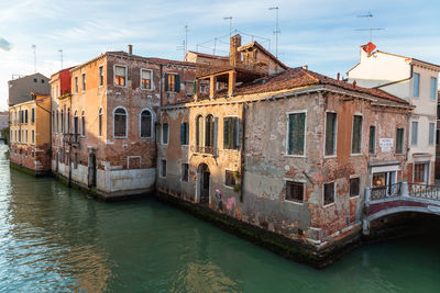 Canal amidst buildings in city against sky