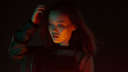 Young woman looking away against black background