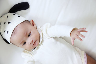 Close-up of baby girl lying on bed