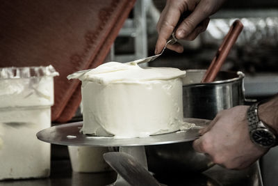 Cropped hands of man making cake in kitchen