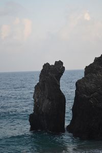 Rock formation in sea against sky