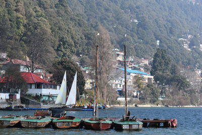 Sailboats moored on sea by mountain