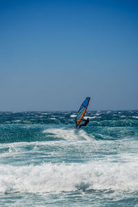 Silhouette man surfing in sea against clear blue sky
