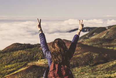 Rear view of woman standing on landscape against sky