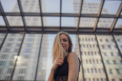 Portrait of smiling young woman standing against buildings in city