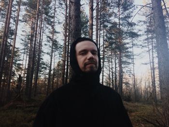 Portrait of man standing against trees at forest