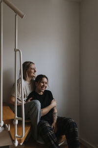 Smiling homosexual couple sitting on wooden stairs