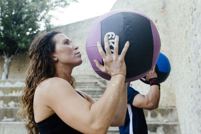 Couple throwing a medicine ball on a wall to practice crossfit.