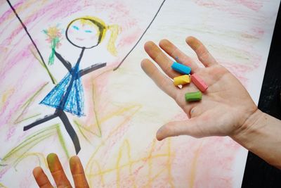 Cropped hands above drawing on table at home