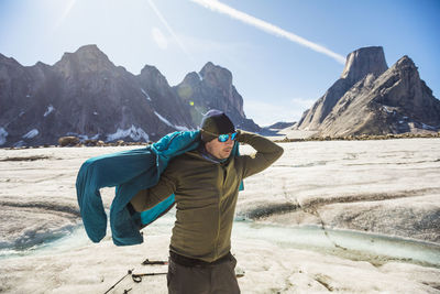 Man standing on snowcapped mountain against sky