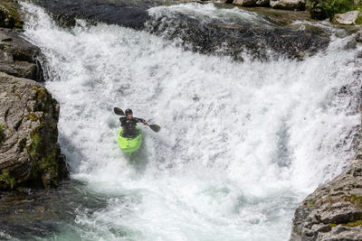 Man surfing on rock in river